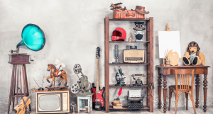 A collection of antique items such as a gramaphone, teddy bear and an old guitar.