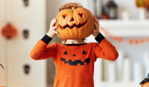 Image of a child playing with pumpkin at home.