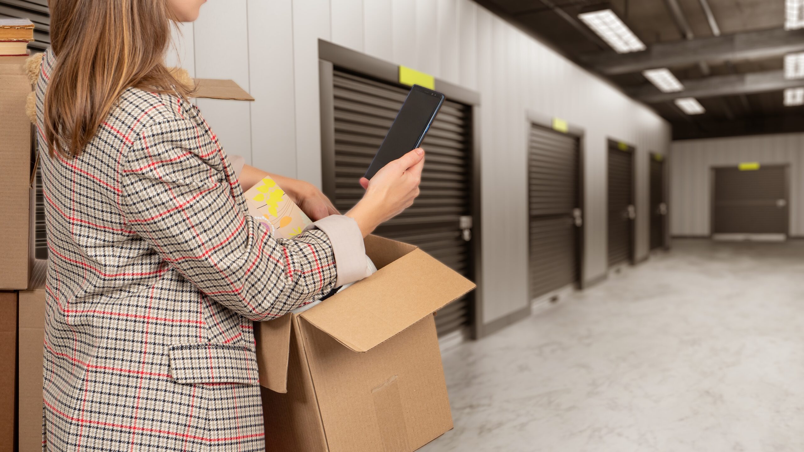 woman holding cardboard box inside self storage unit for businesses