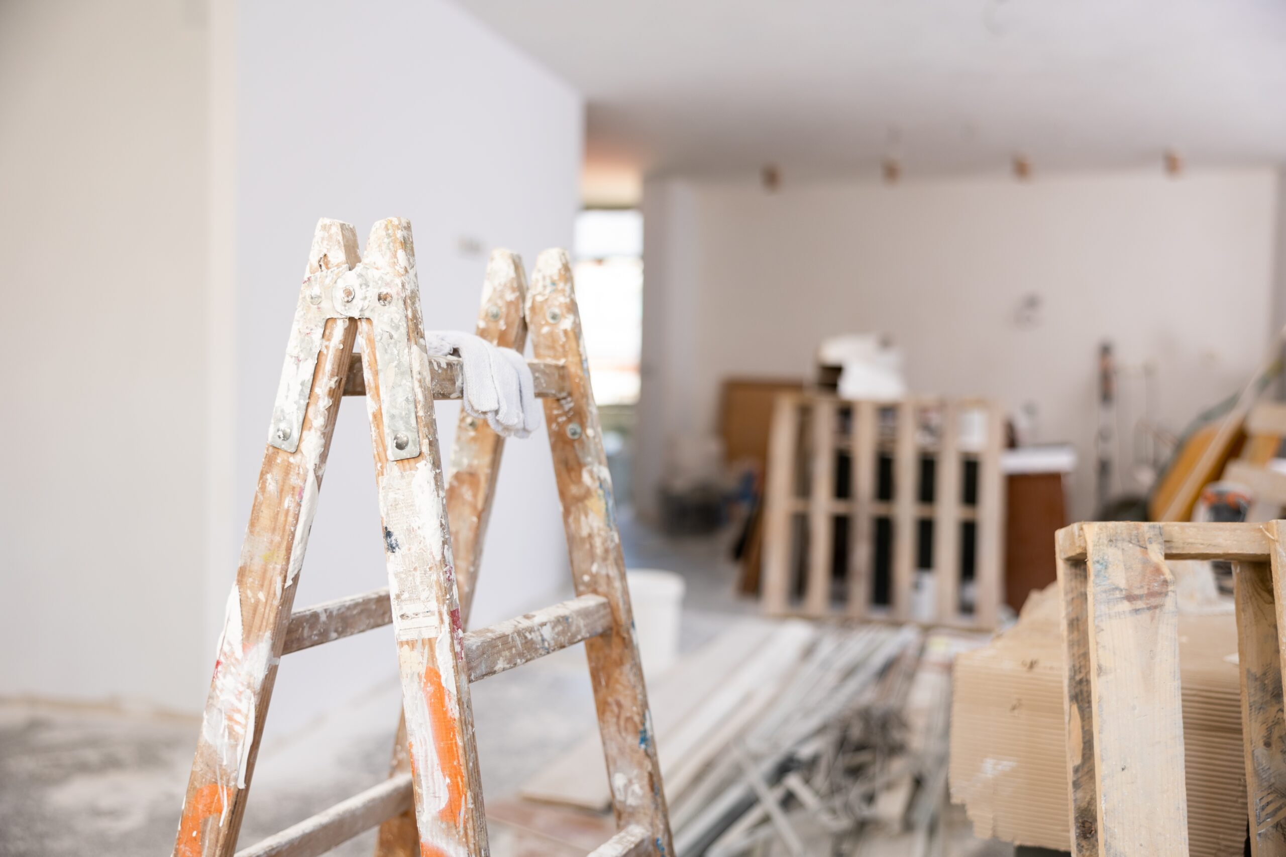 A ladder covered in paint in a house being renovated.