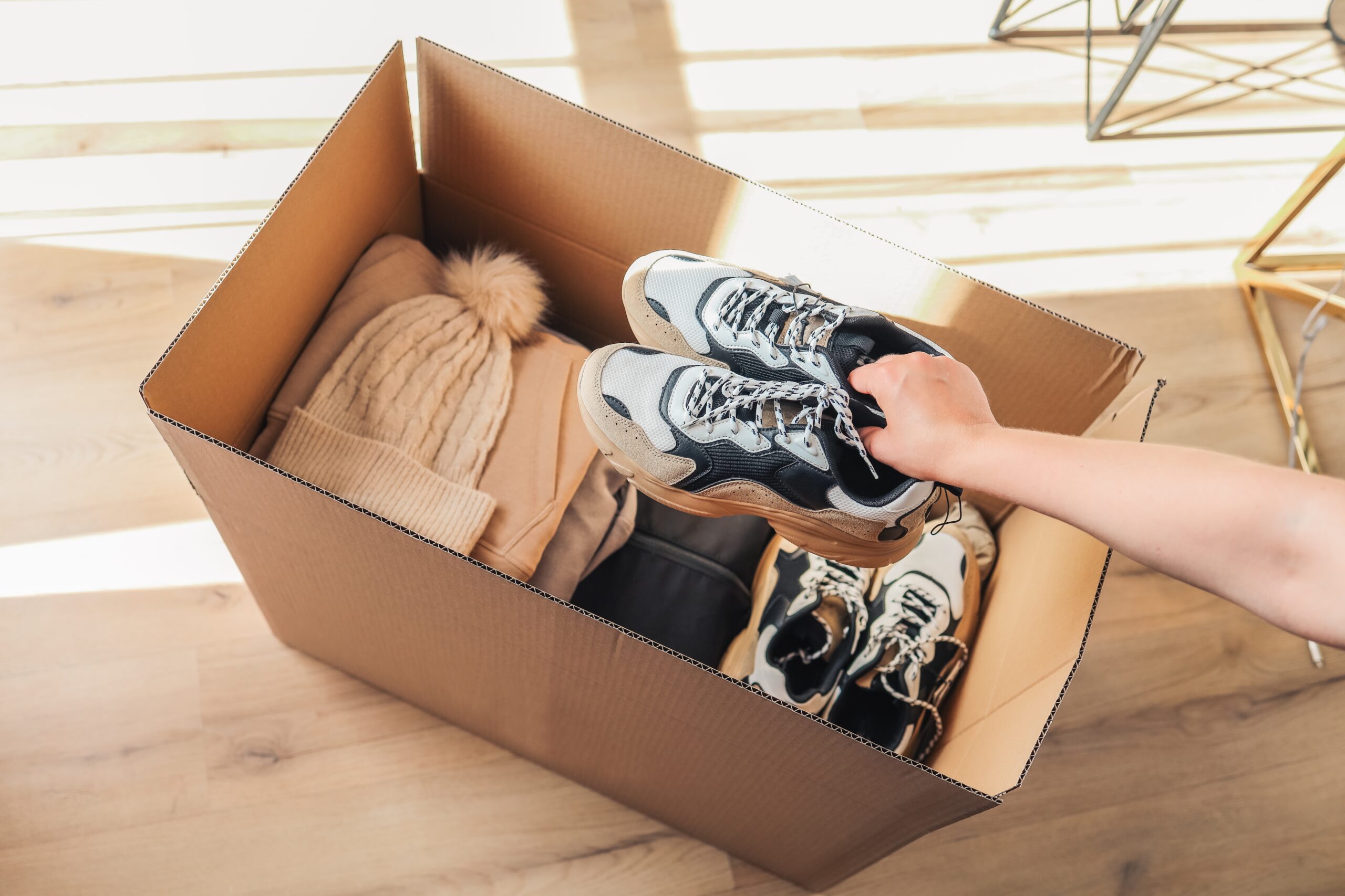 An image of a box with clothes in there and someone packing their university clothes.