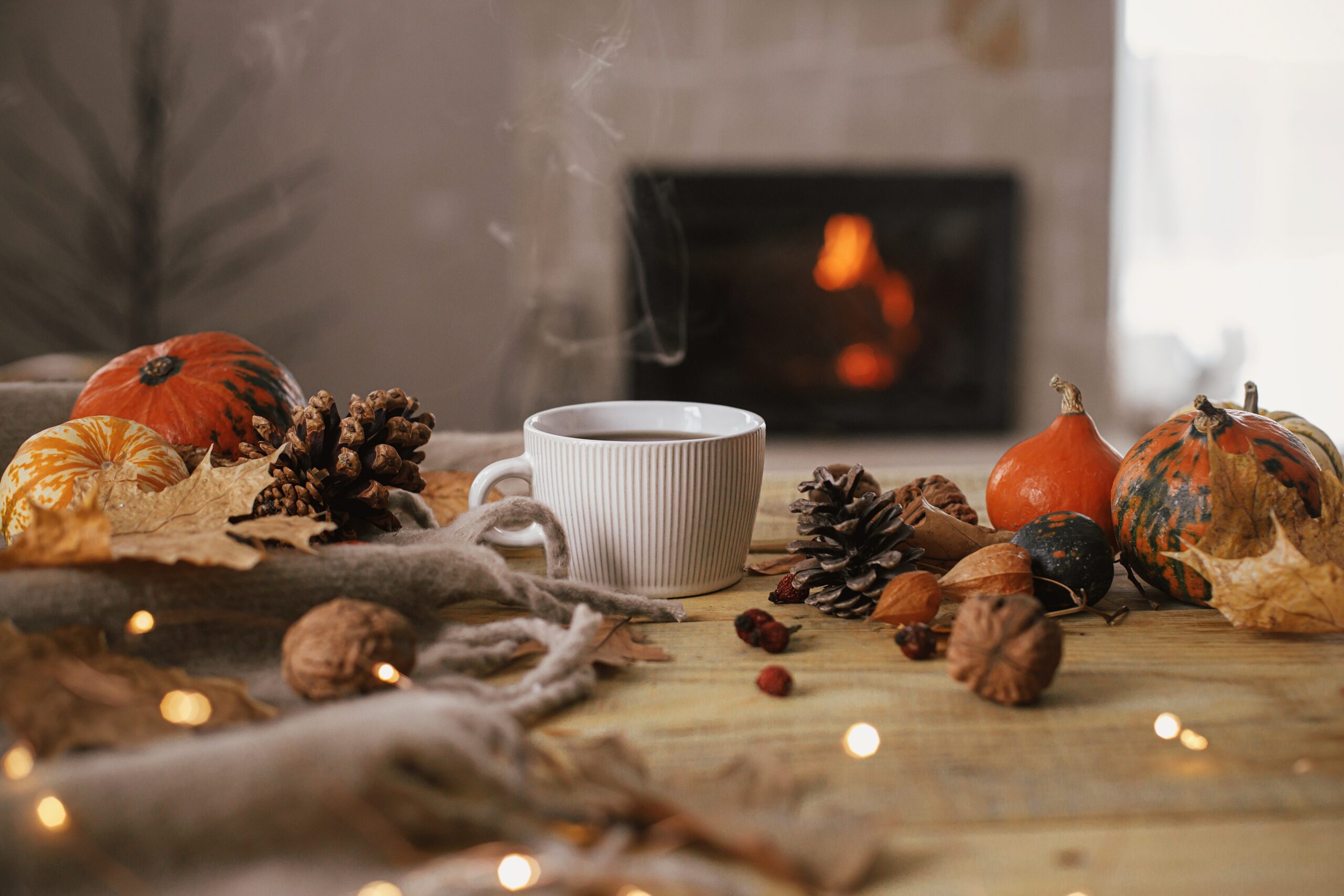 An image of a wooden table with pinecones, conkers, leaves and pumpkins scattered across it.