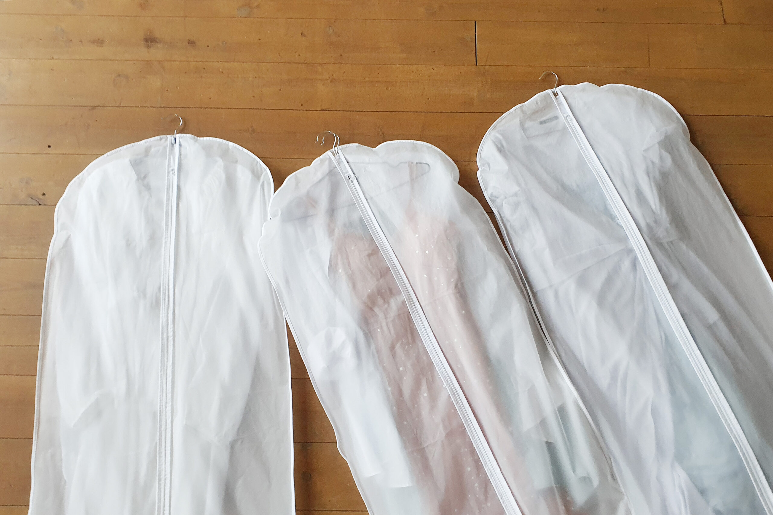 Three white clothes hanging bags.