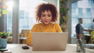 A woman smiling and looking at her laptop.