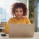 A woman smiling and looking at her laptop.