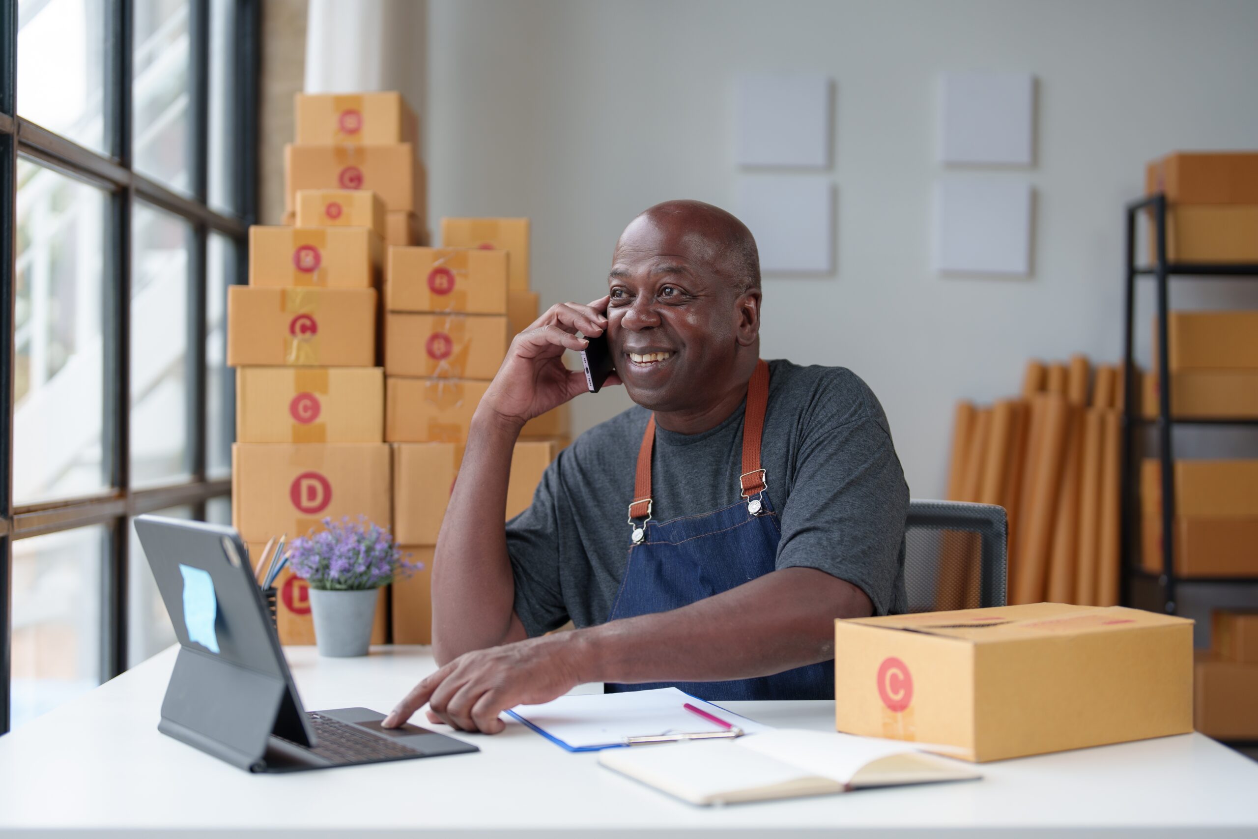 A man on the phone with lots of boxes behind him.