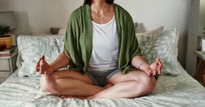 An image of a woman meditating on her bed.
