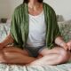 An image of a woman meditating on her bed.