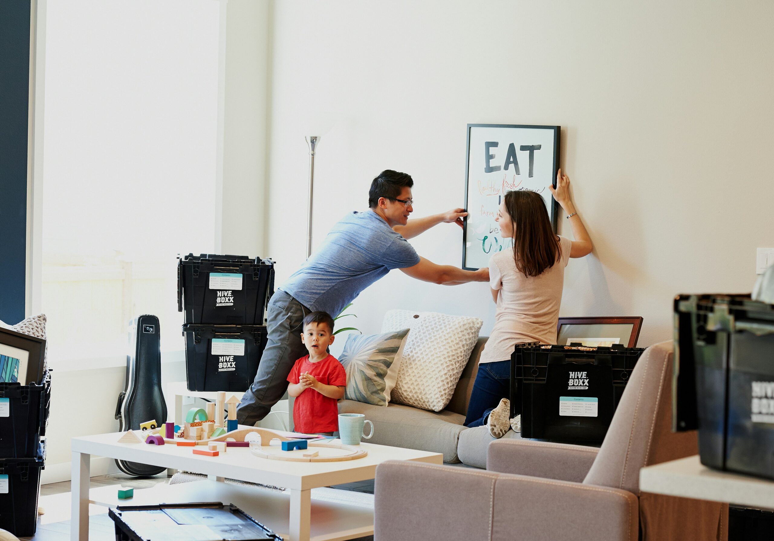 A couple putting up a canvas on their wall in their living room.